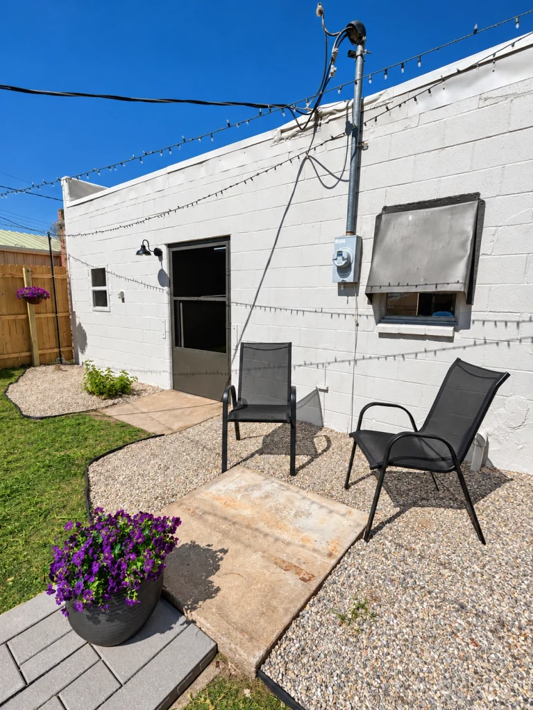 Home Rear entrance to the commercial building with concrete patio, outdoor chairs, and planters.
