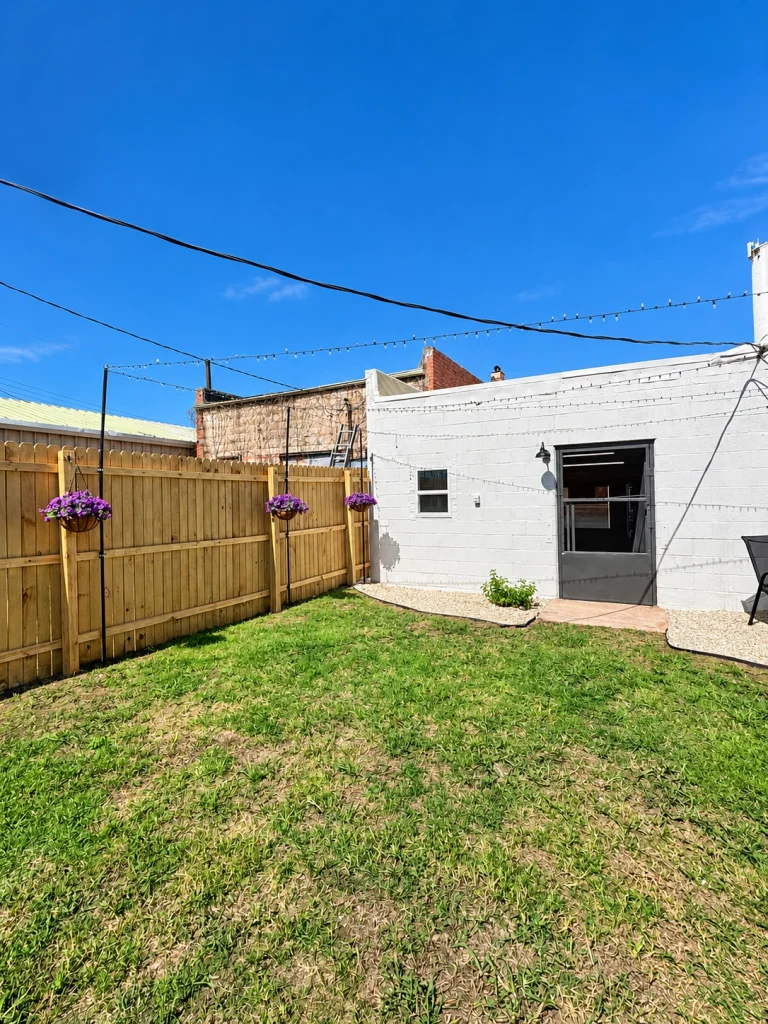 Home Angled view of the building's rear exterior and fenced backyard.