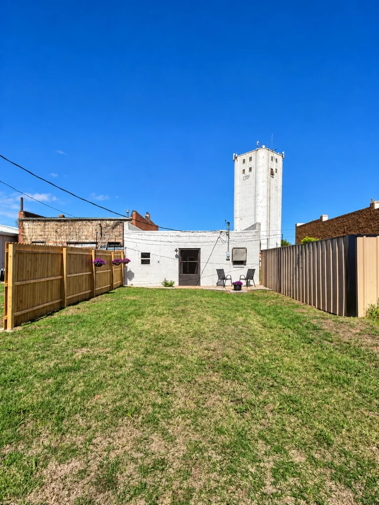 Home Full-length view of the grassy rear yard leading to the commercial building.