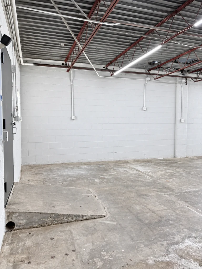 Home Interior side wall showing ramp off back door and exposed metal ceiling structure of the commercial building.