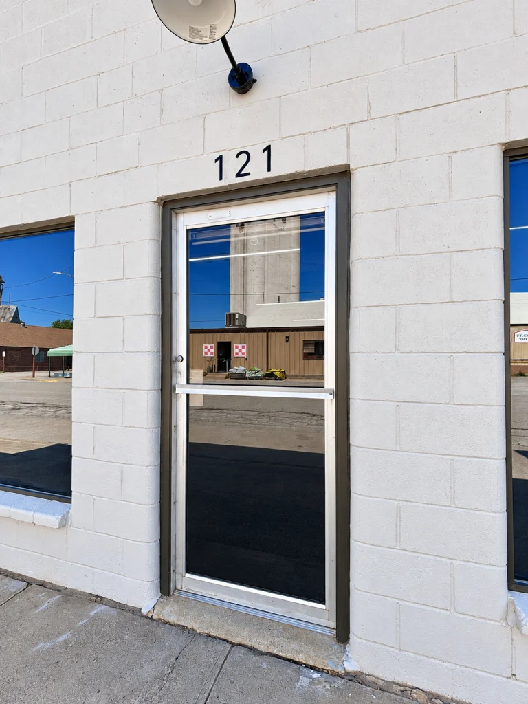 Home Close-up of the storefront glass entry door with the address number 121 above it.